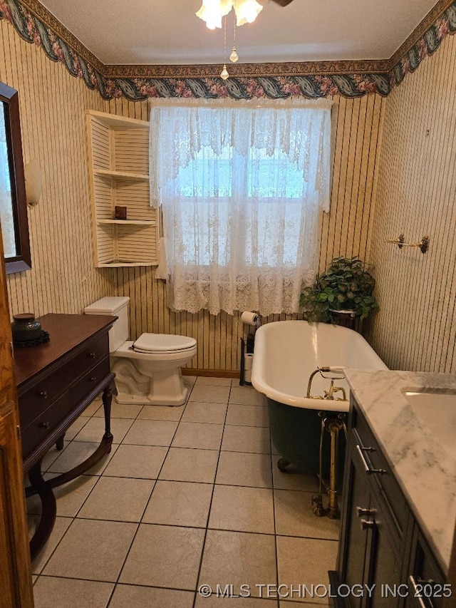 bathroom featuring tile patterned flooring, vanity, a washtub, ceiling fan, and toilet