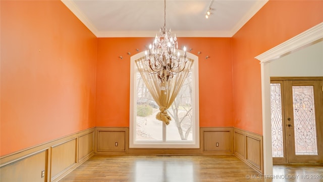 interior space featuring ornamental molding, light hardwood / wood-style flooring, a notable chandelier, and french doors