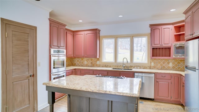 kitchen with sink, stainless steel appliances, a center island, tasteful backsplash, and light stone countertops