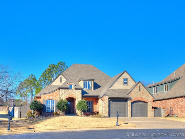 french country style house with fence, roof with shingles, concrete driveway, stone siding, and a garage