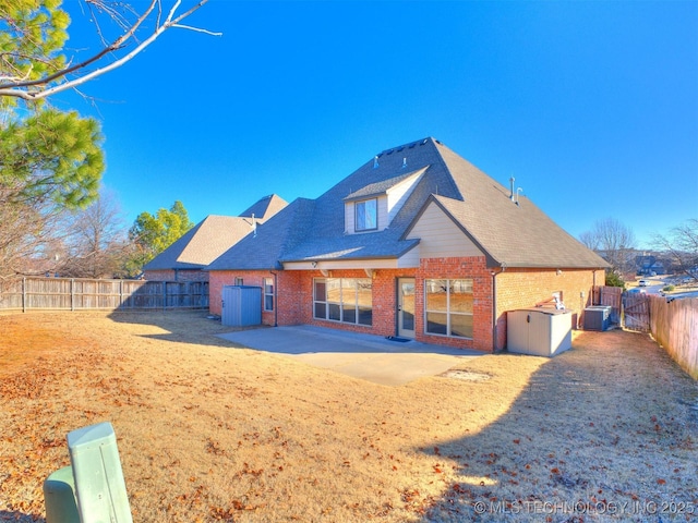 rear view of property featuring a patio, a fenced backyard, cooling unit, roof with shingles, and brick siding