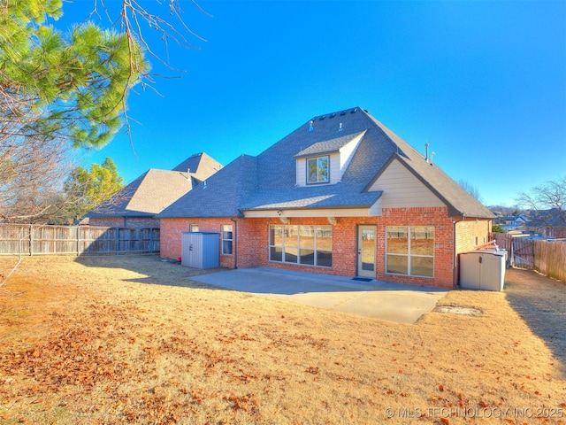 back of property featuring a shed, a patio area, brick siding, and a fenced backyard