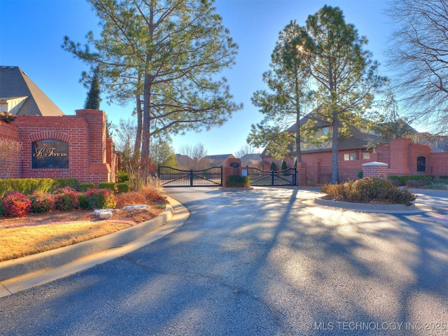 view of street featuring a gated entry, curbs, and a gate