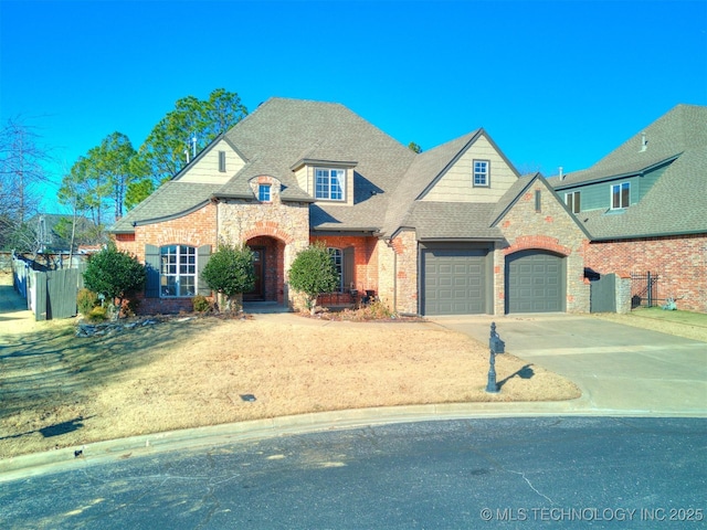 french provincial home featuring concrete driveway, brick siding, a garage, and a shingled roof