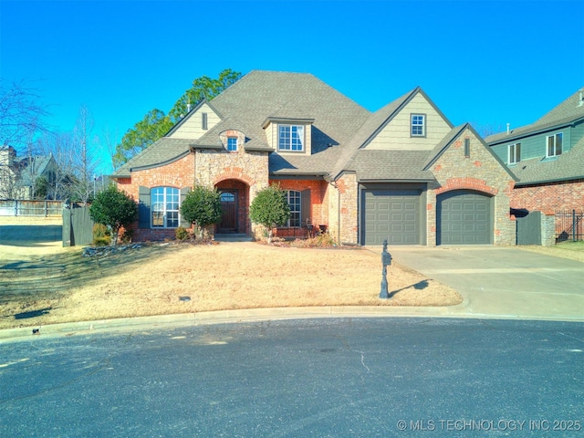 french country style house with an attached garage, fence, roof with shingles, stone siding, and driveway