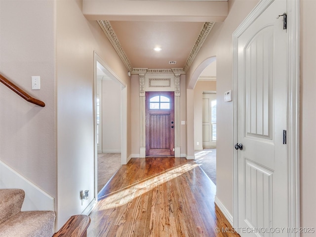 entrance foyer with visible vents, light wood-type flooring, stairway, arched walkways, and baseboards