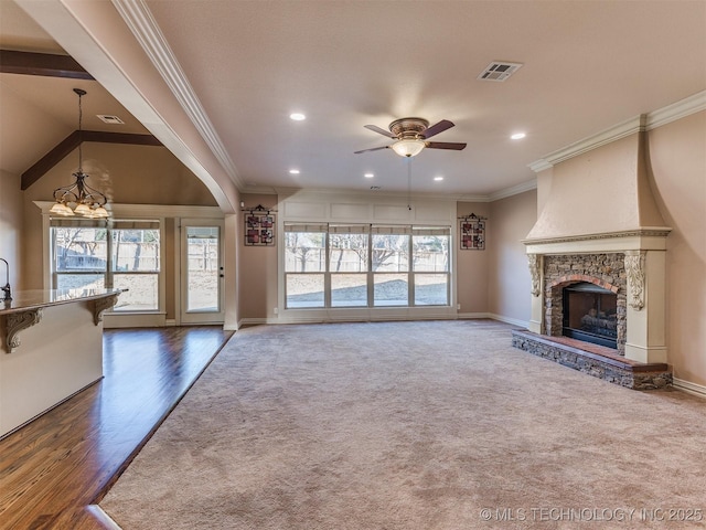 unfurnished living room with a stone fireplace, visible vents, a wealth of natural light, and ornamental molding