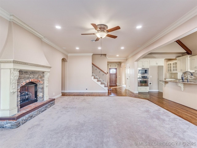 unfurnished living room featuring dark wood-style floors, a fireplace, stairs, and crown molding