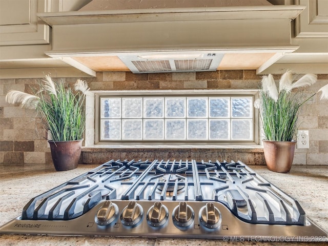 interior details featuring premium range hood, cream cabinets, light stone countertops, and cooktop