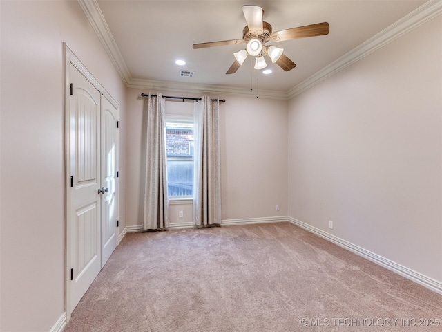 spare room with baseboards, visible vents, ceiling fan, ornamental molding, and carpet flooring