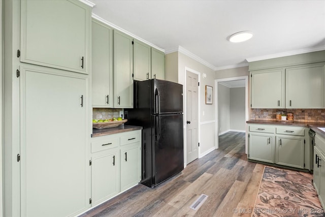 kitchen featuring visible vents, dark countertops, wood finished floors, freestanding refrigerator, and crown molding