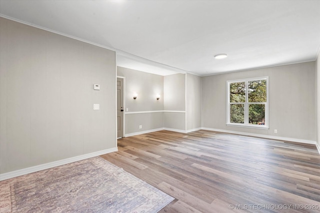 spare room featuring light wood-style flooring, baseboards, and ornamental molding