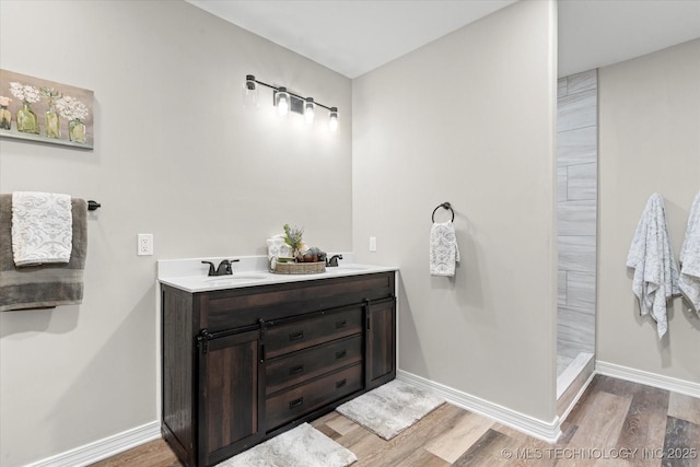 bathroom featuring wood finished floors, baseboards, and double vanity