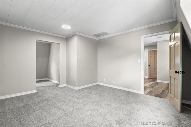 carpeted empty room with ornamental molding, visible vents, and baseboards