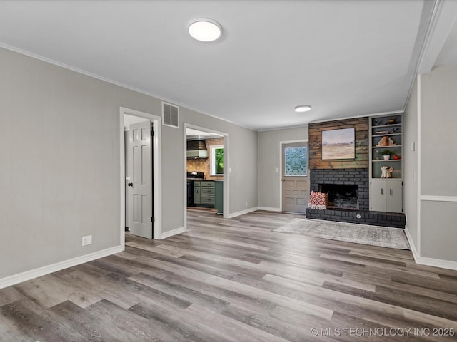2936 Ridge Rd, Bartlesville, OK 74006 - unfurnished living room with a brick fireplace, wood finished floors, ornamental molding, and built in shelves