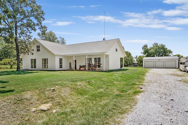 back of property featuring a garage, a lawn, and an outdoor structure