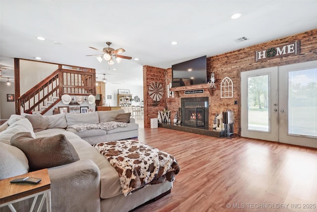 living room with french doors, ceiling fan, a fireplace, and hardwood / wood-style floors