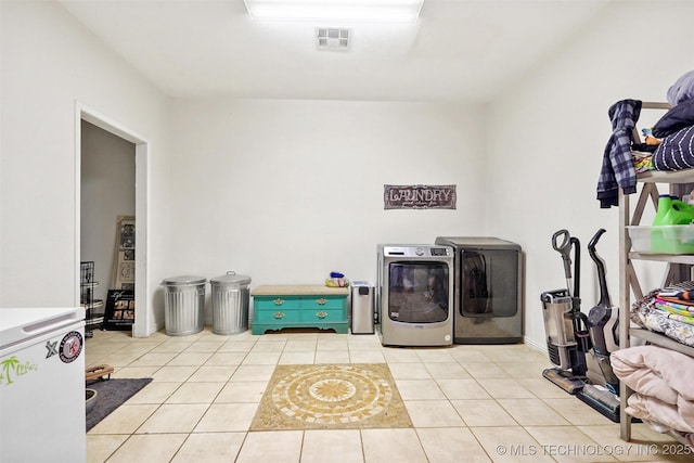 clothes washing area with light tile patterned flooring and washer and clothes dryer