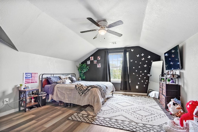 bedroom with lofted ceiling, a textured ceiling, wood-type flooring, and ceiling fan