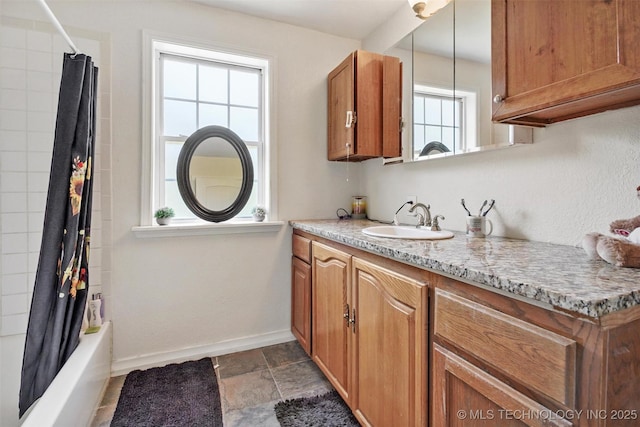 kitchen featuring sink, decorative light fixtures, and light stone countertops