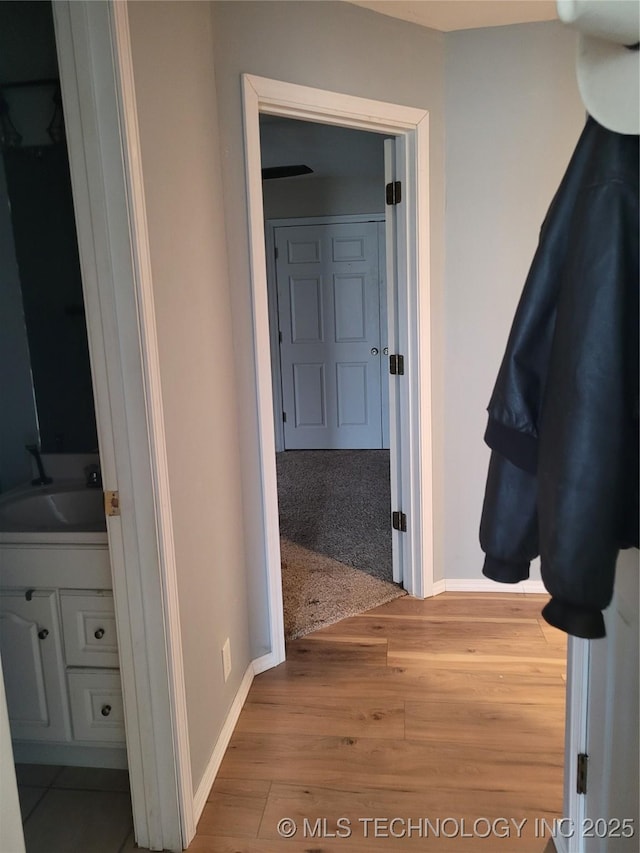 corridor featuring sink and light wood-type flooring