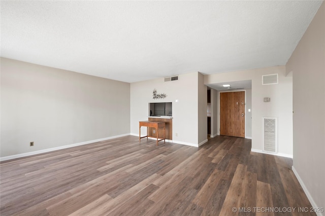 unfurnished living room with dark hardwood / wood-style flooring and a textured ceiling