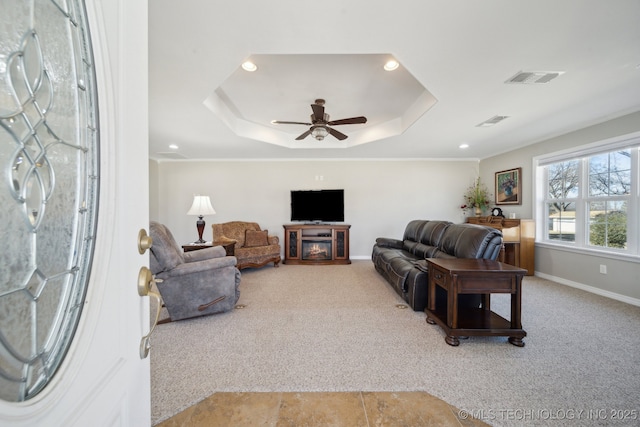 carpeted living room with a fireplace, a raised ceiling, and ceiling fan