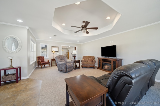 living room featuring a raised ceiling, ornamental molding, light colored carpet, and ceiling fan