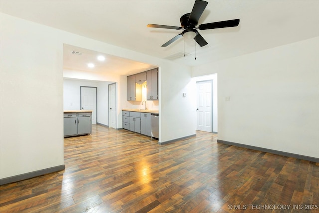 unfurnished living room with a ceiling fan, baseboards, visible vents, a sink, and dark wood-style floors
