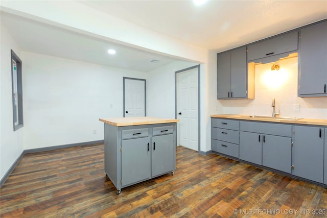 kitchen with gray cabinets, sink, wooden counters, a center island, and dark wood-type flooring