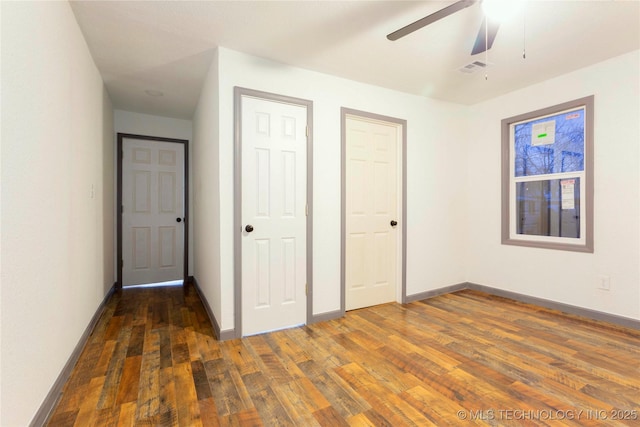 unfurnished bedroom with wood finished floors, visible vents, ceiling fan, two closets, and baseboards