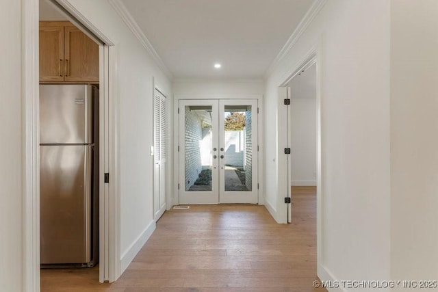 hall with french doors, ornamental molding, and light hardwood / wood-style flooring