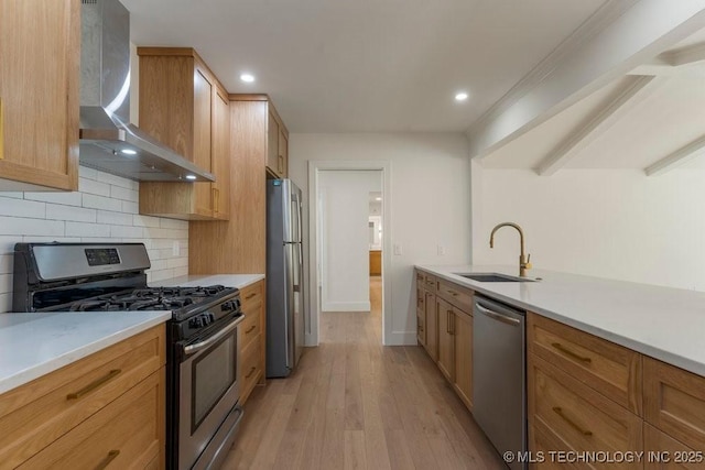 kitchen featuring sink, tasteful backsplash, appliances with stainless steel finishes, light hardwood / wood-style floors, and wall chimney range hood