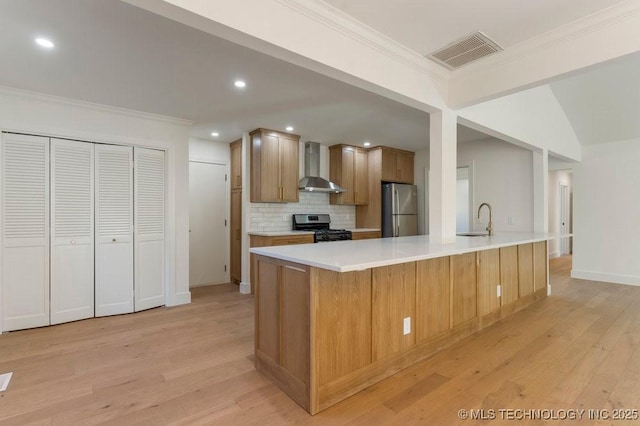 kitchen featuring stainless steel refrigerator, sink, decorative backsplash, range, and wall chimney range hood