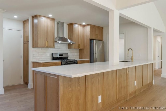 kitchen featuring sink, tasteful backsplash, appliances with stainless steel finishes, a kitchen island with sink, and wall chimney range hood