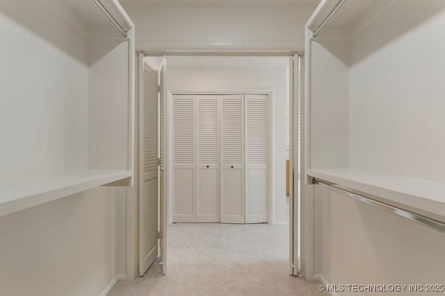 walk in closet featuring light colored carpet