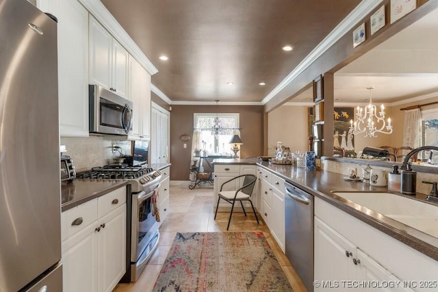 kitchen featuring stainless steel appliances, a notable chandelier, white cabinets, and decorative light fixtures