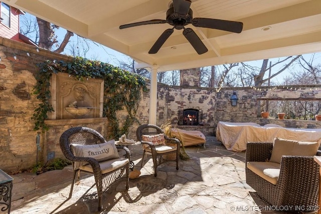 view of patio with an outdoor living space with a fireplace and ceiling fan