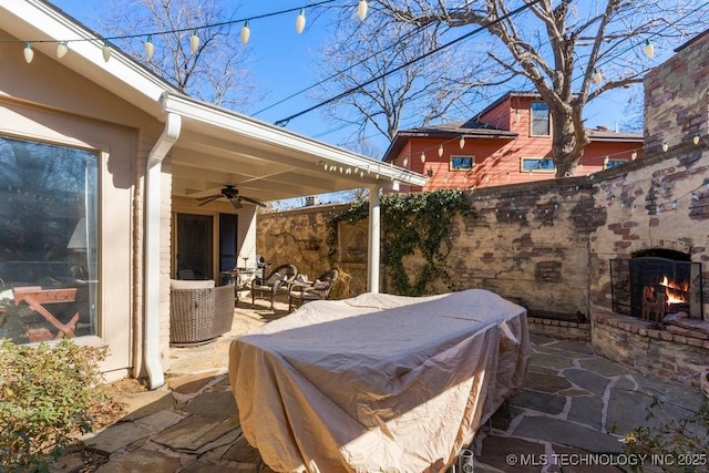 view of patio / terrace with ceiling fan and an outdoor stone fireplace