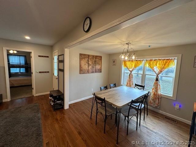 dining space featuring dark wood-type flooring and a notable chandelier