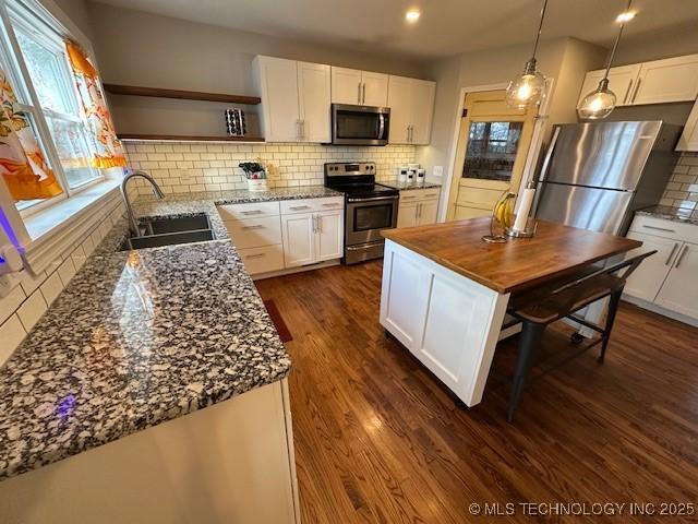 kitchen with stainless steel appliances, white cabinetry, and sink