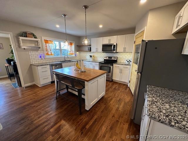 kitchen with stainless steel appliances, white cabinetry, sink, and dark hardwood / wood-style floors