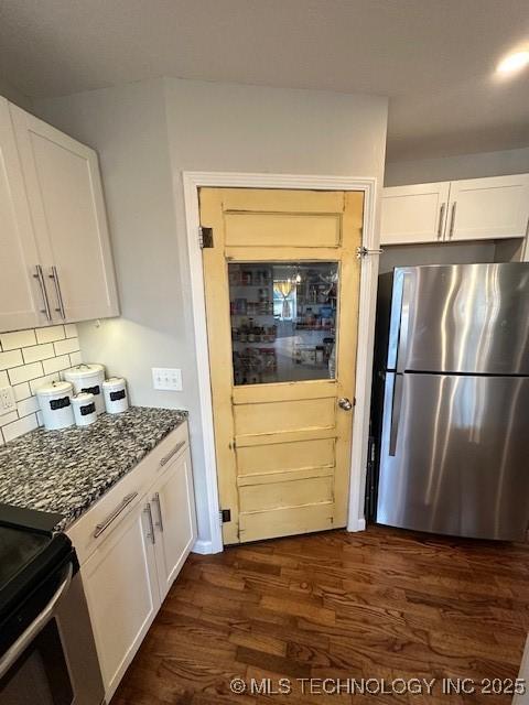 kitchen featuring stainless steel refrigerator, dark stone countertops, dark hardwood / wood-style floors, white cabinets, and decorative backsplash