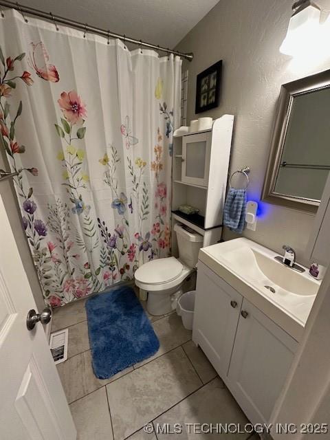 bathroom with tile patterned flooring, vanity, walk in shower, and toilet