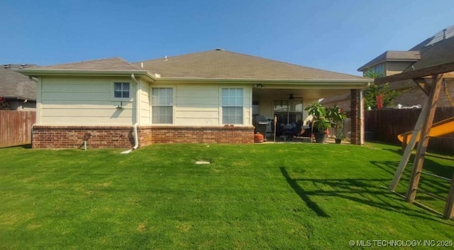 back of property featuring a yard, brick siding, fence, and a ceiling fan