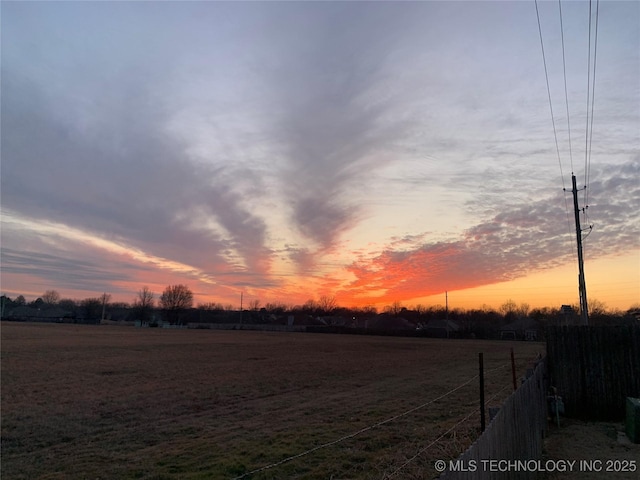 yard at dusk with a rural view and fence