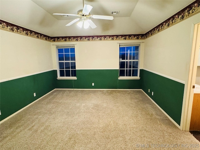 carpeted spare room featuring ceiling fan, visible vents, vaulted ceiling, and baseboards