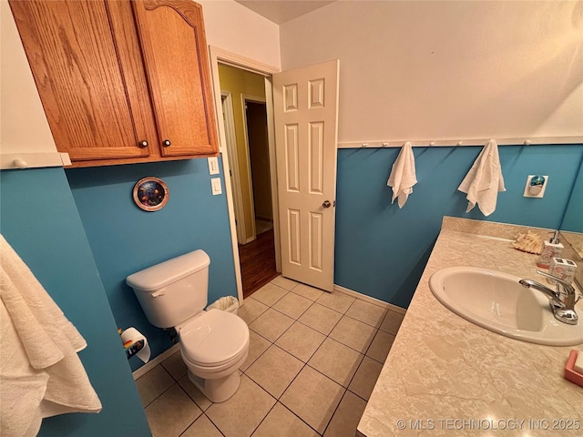 bathroom with toilet, vanity, baseboards, and tile patterned floors