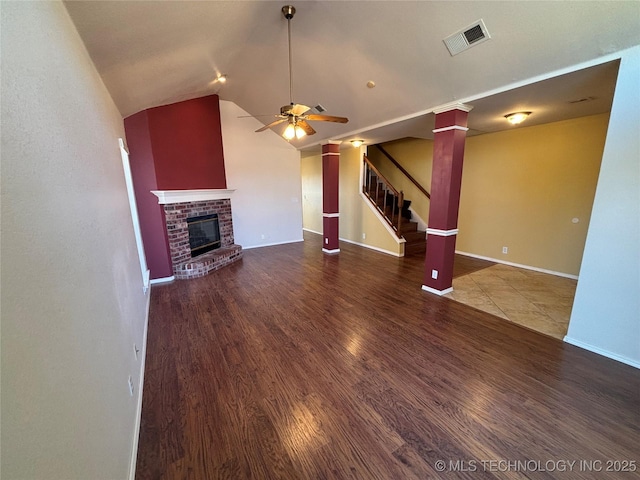 unfurnished living room featuring visible vents, stairway, wood finished floors, vaulted ceiling, and a fireplace