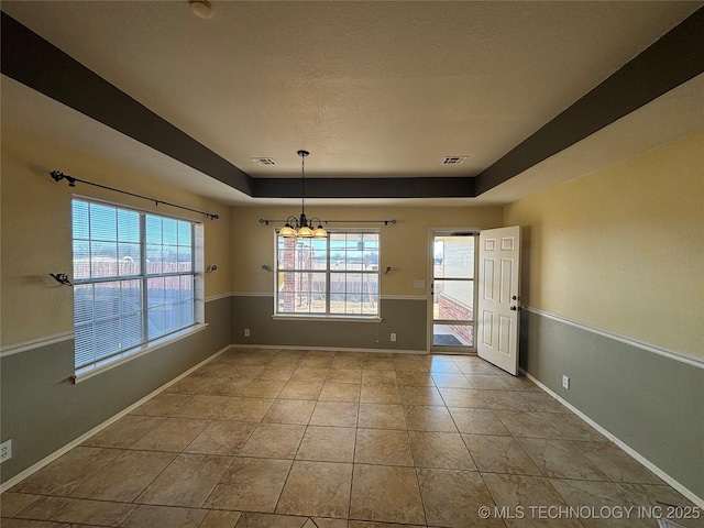 empty room featuring a tray ceiling, tile patterned flooring, visible vents, and baseboards